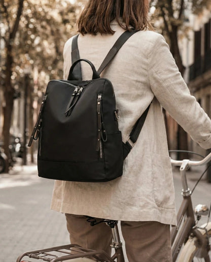 Person with a black backpack riding a bicycle on a street.
